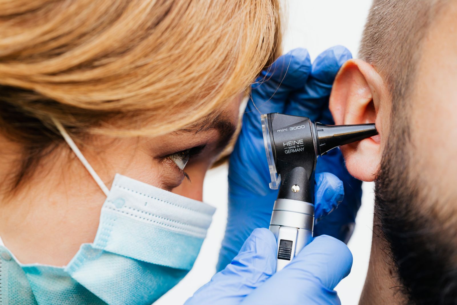 A clinician examining a patient’s ear with an otoscope