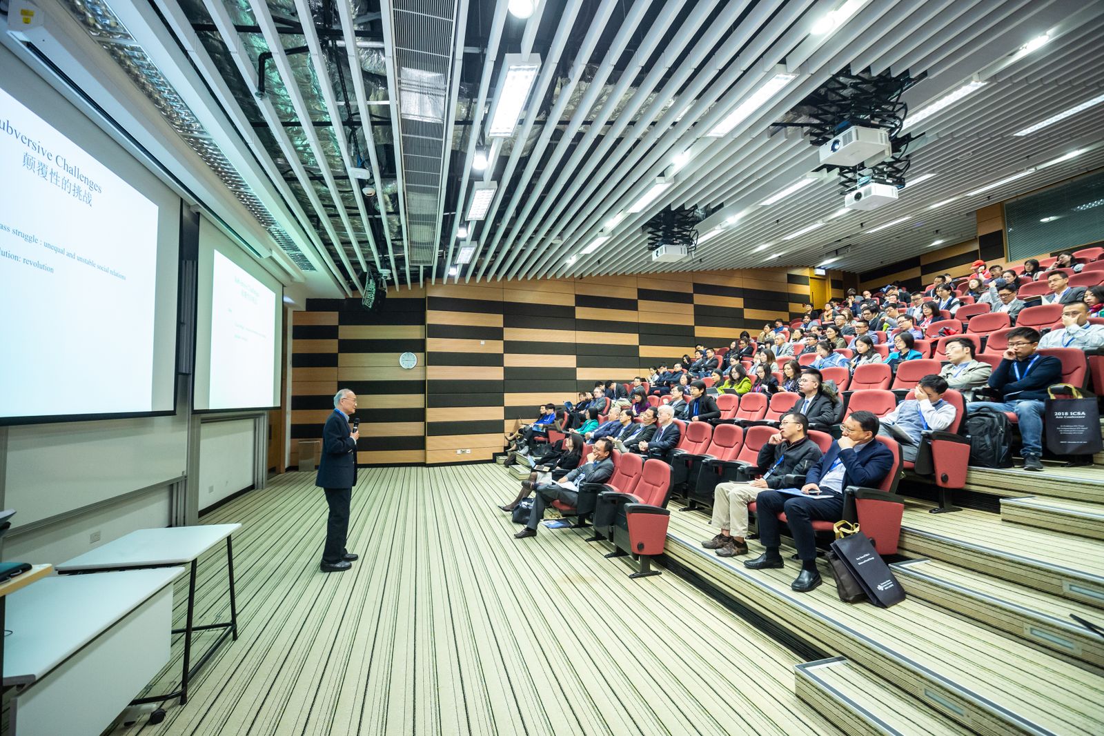 A speaker addresses a full lecture hall