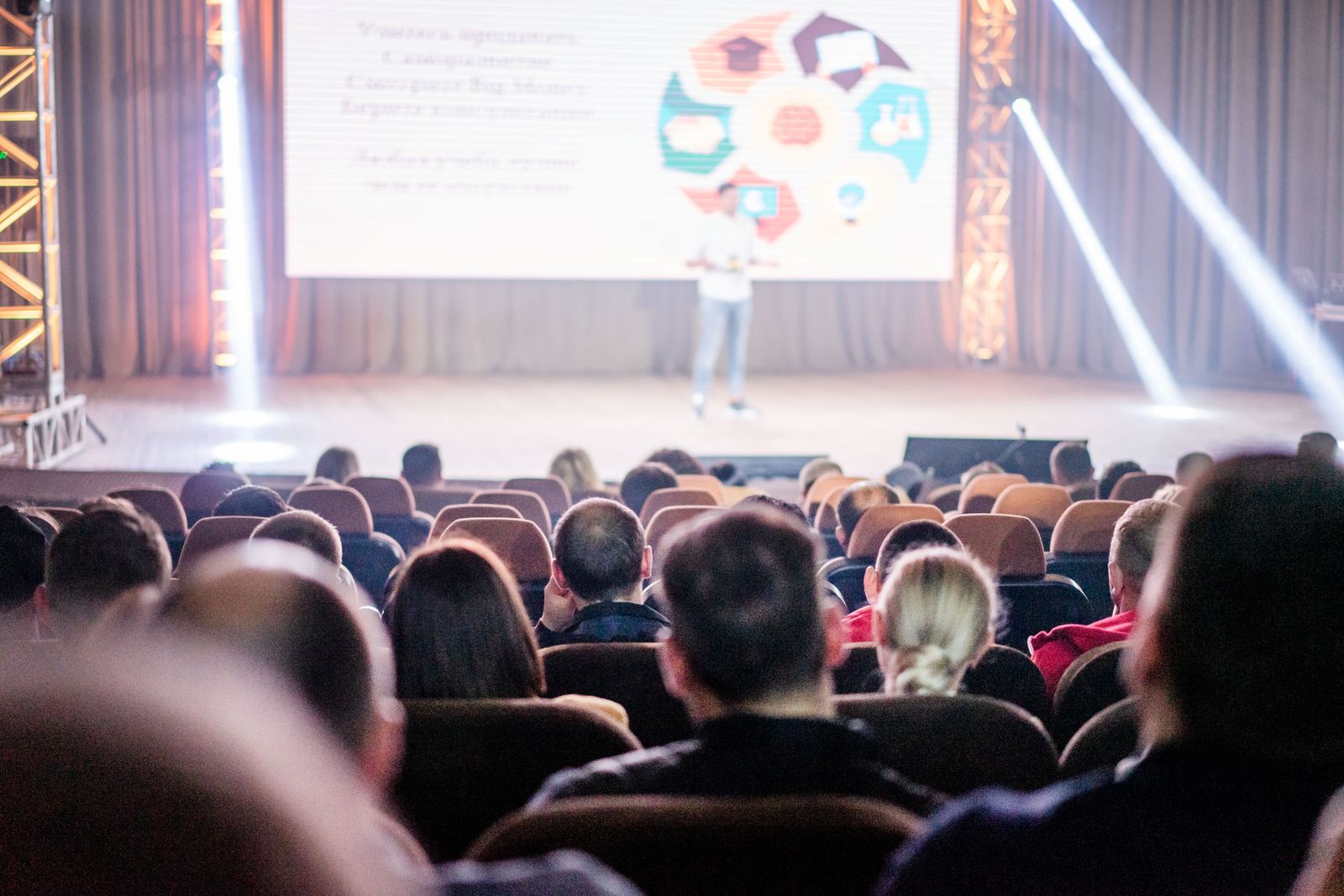 An audience follows a presentation on a large stage